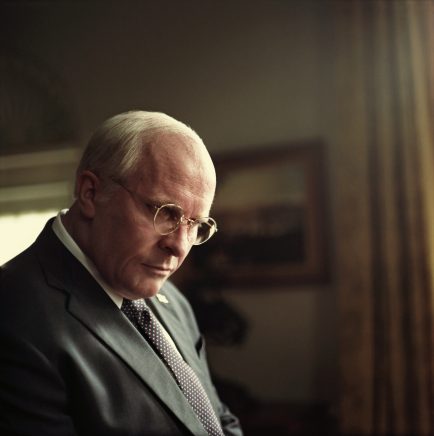 A man resembling American ex vice president Dick Cheney stands in the White House's oval office. He wears a light grey suit, and his hair is receding and white. He gazes downward thoughtfully, with silver framed glasses on the bridge of his nose. This image is from the film Vice, out in cinemas Friday 25 January.